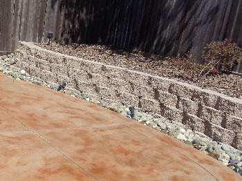 Engineered interlocking concrete block retaining wall for hillside erosion control