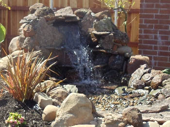 Natural stone pondless waterfall with LED lighting and aquatic plants